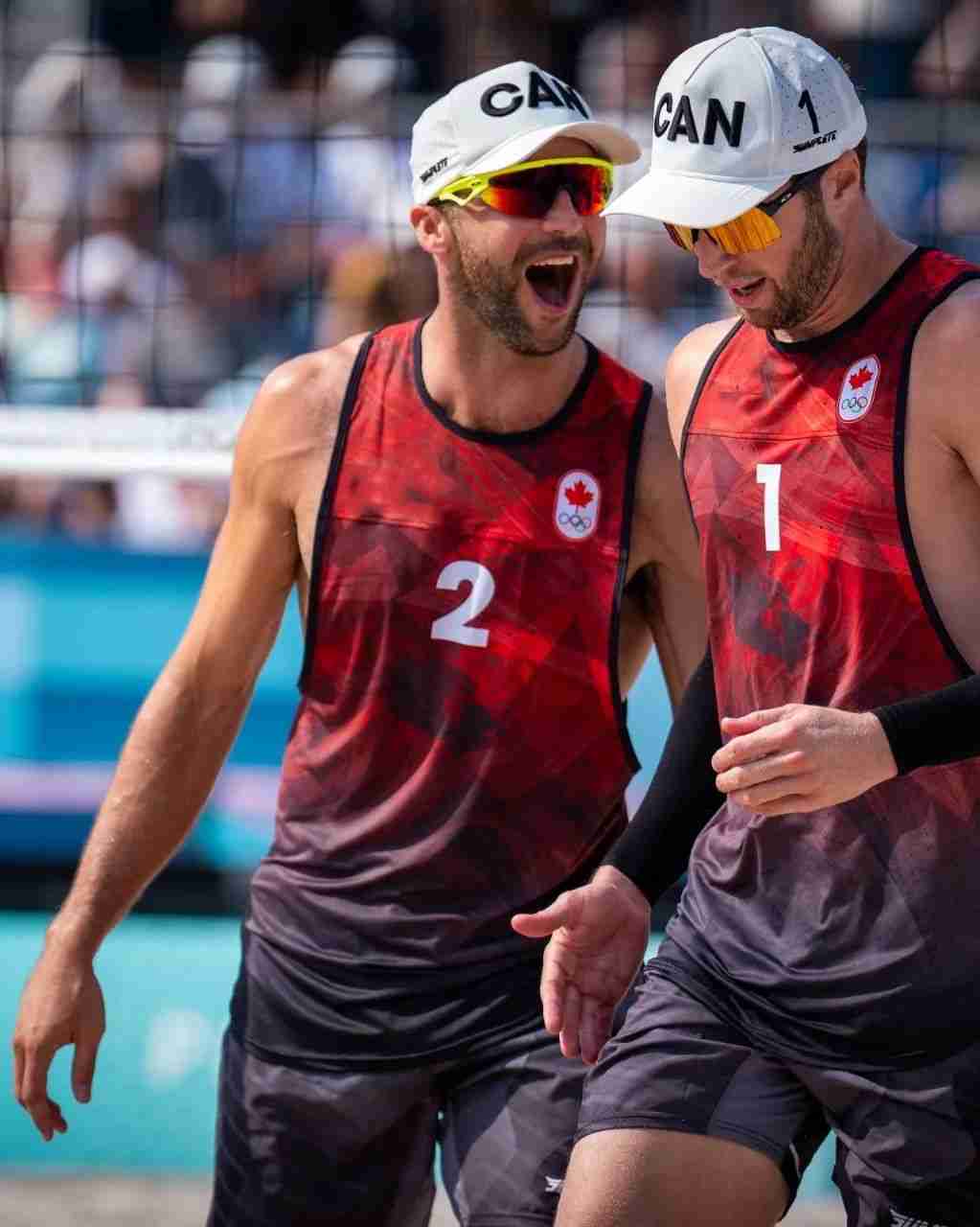 Two beach volleyball players wearing matching red and black sleeveless uniforms