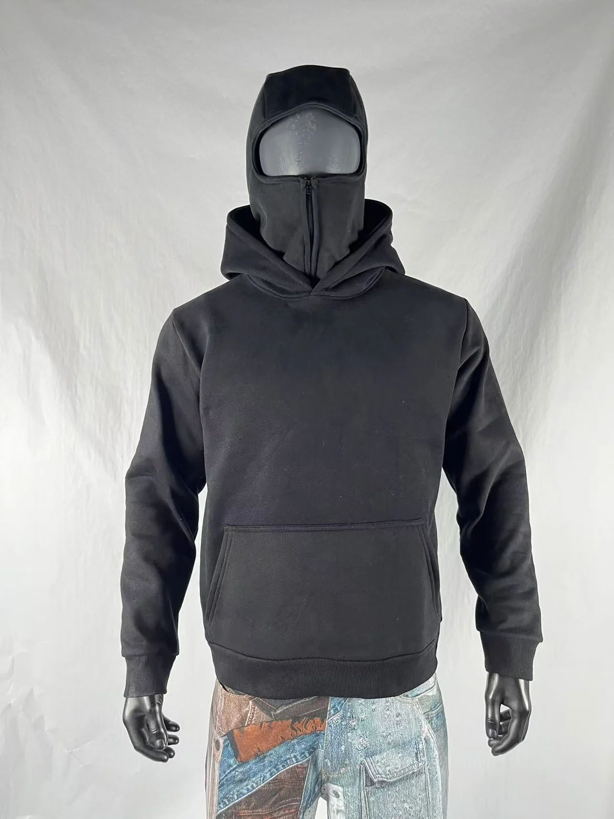 Dark pullover balaclava hoodie on a mannequin with the outer hood down and face-cover zipper closed