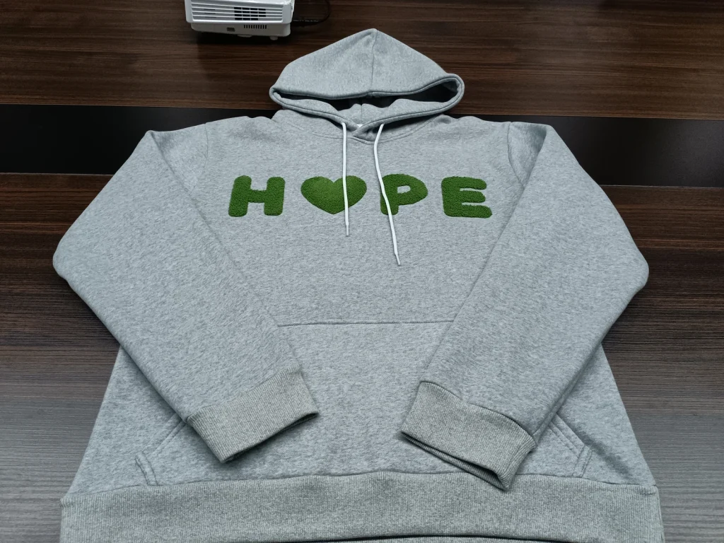 Gray pullover hoodie with green raised chest lettering and white drawcords