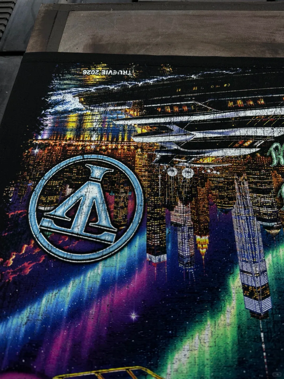 Close view of bright city lights and a circular outlined symbol within a large print on dark fabric