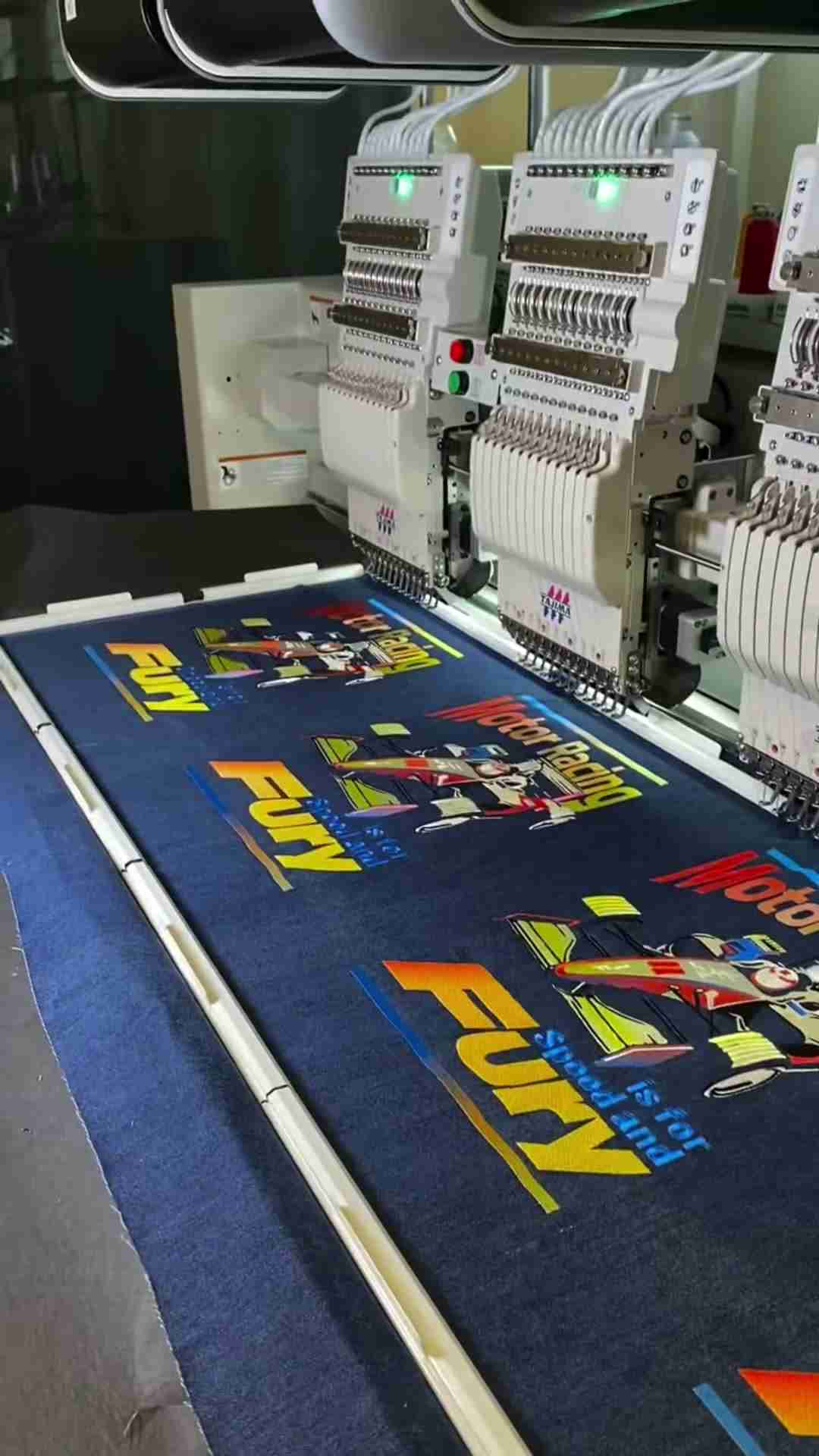 Yellow-to-orange gradient embroidery lettering beside a multicolor stitched motif on dark fabric