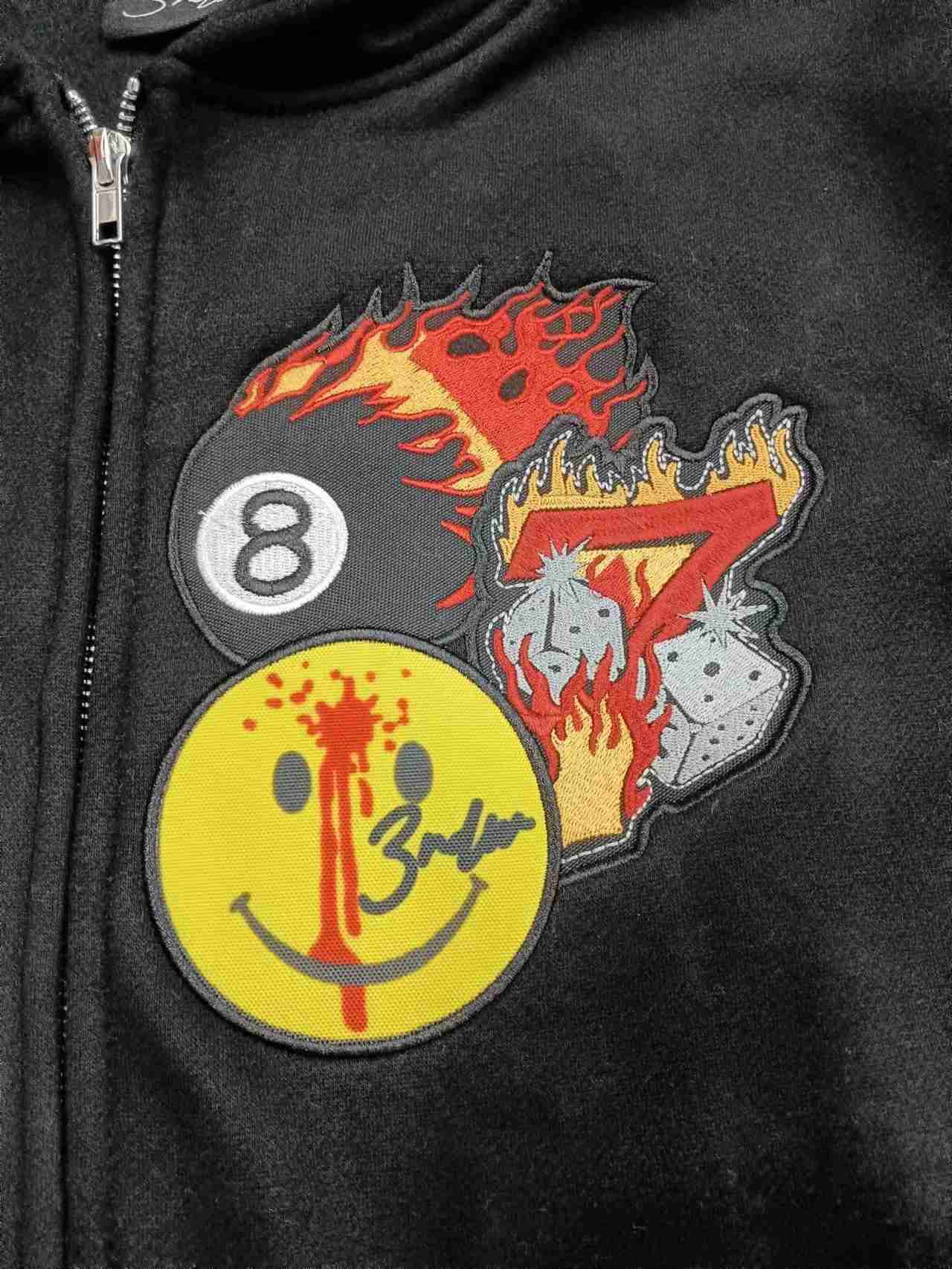 Close-up of stitched details and outlined shapes on a black hoodie chest