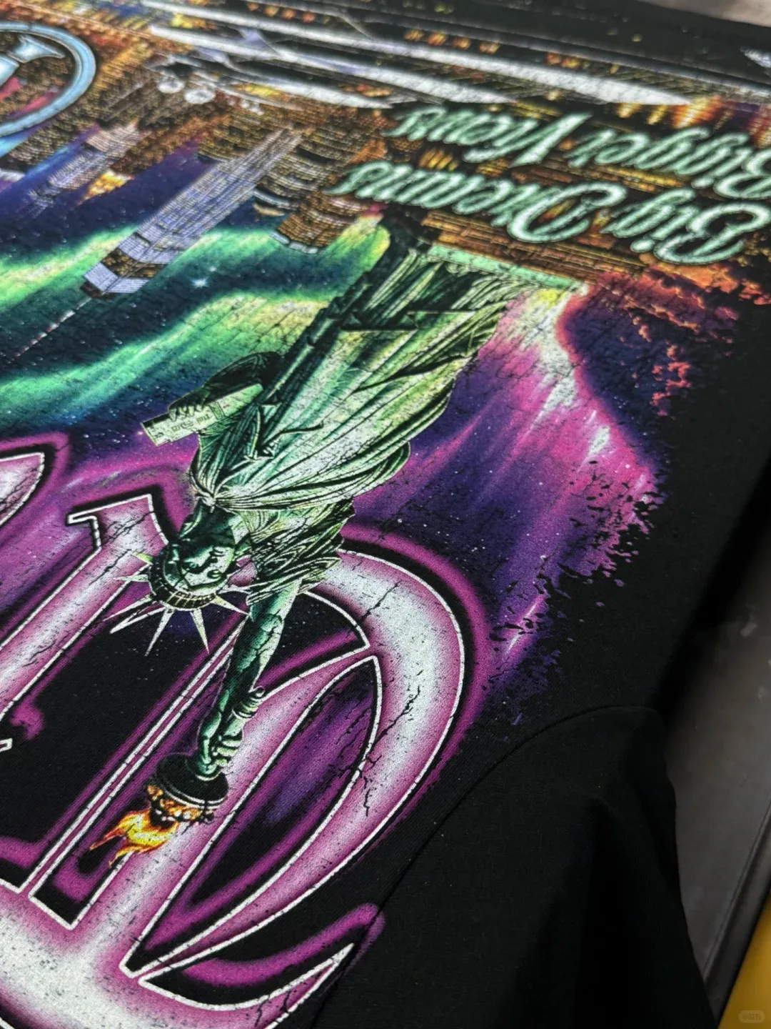 Close-up of a large purple and green graphic with a statue motif printed on dark fabric