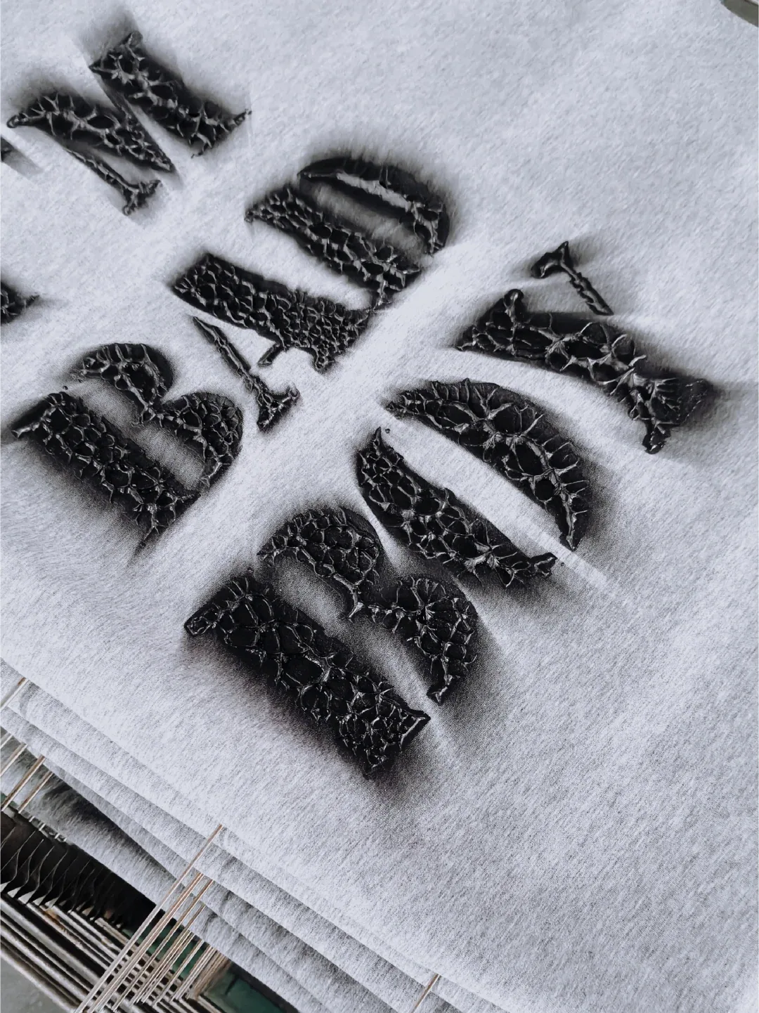 Overview of black raised rock-texture letters across folded light gray fabric